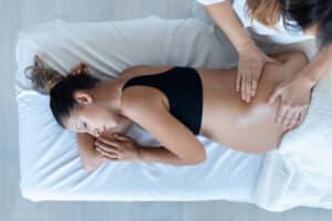 Shot of physiotherapist woman massaging tummy on pregnant woman.
